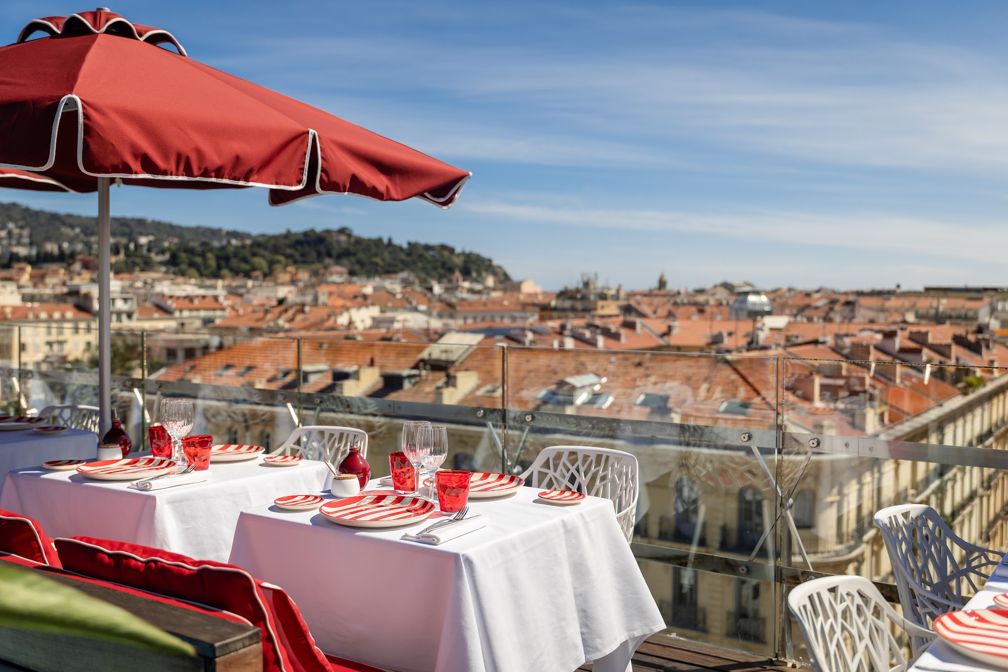 Tables dressées sur la terrasse du BCLUB Rooftop du Boscolo Nice avec vue sur les toits niçois