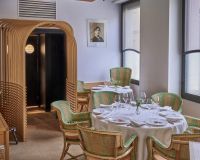 Salle du restaurant L'Arpège à Paris, fauteuils en rotin vert et tables dressées