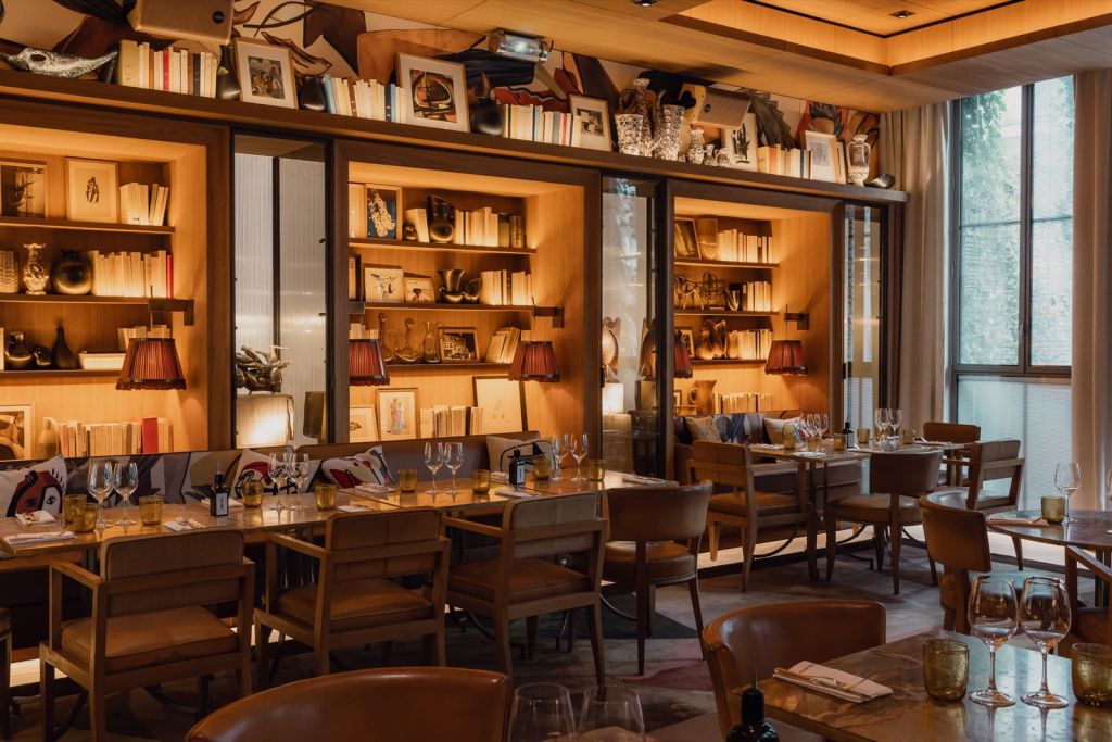 Salle du restaurant du Brach Paris, bibliothèques éclairées et tables dressées