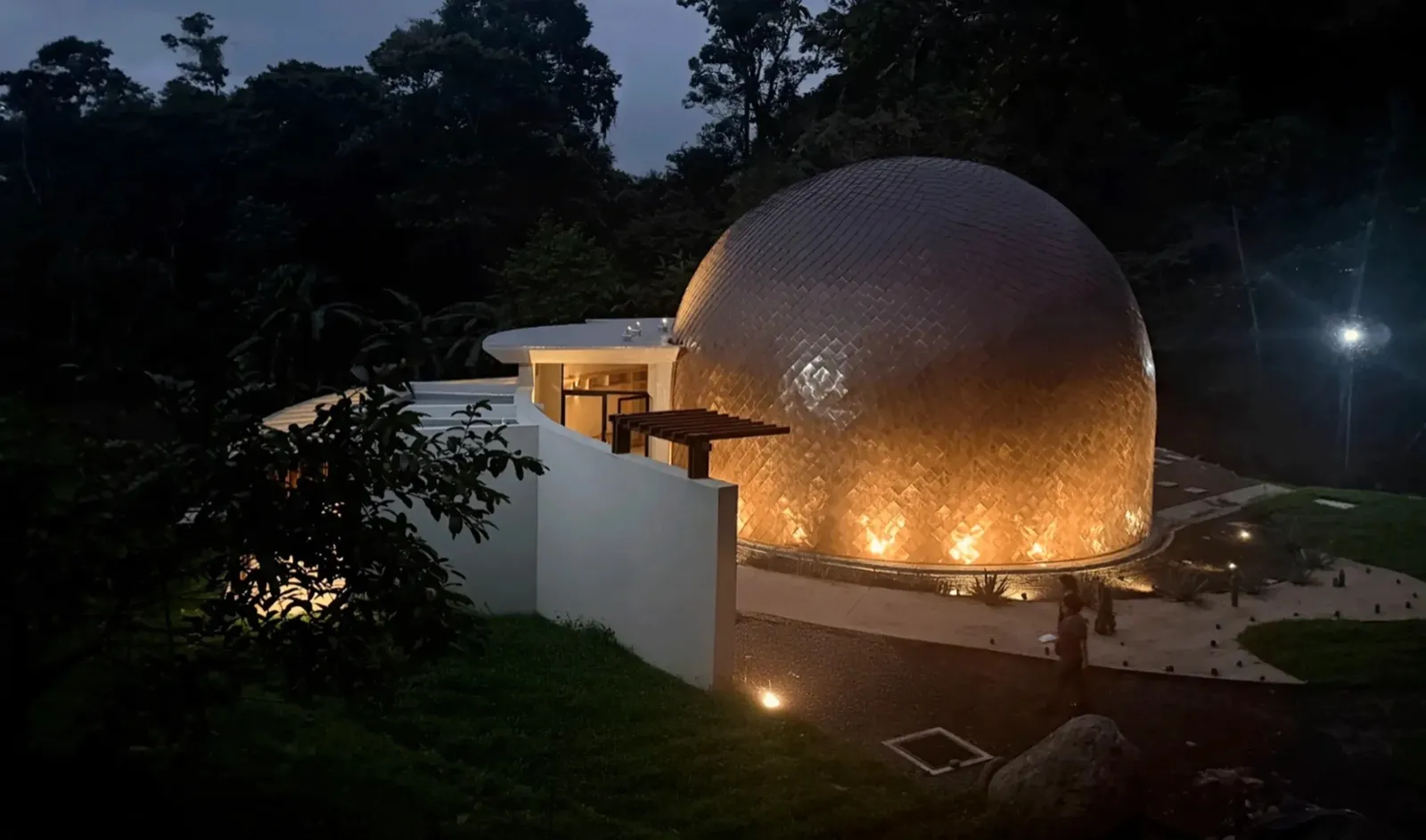 Le dôme de fréquence de The Vessyl illuminé à la nuit tombée dans la forêt costaricienne
