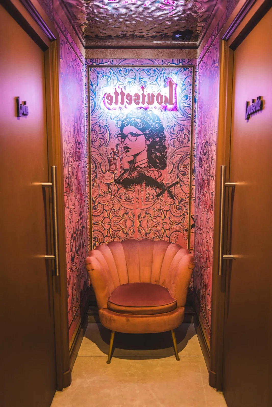Couloir intérieur de Louisette avec fauteuil coquillage rose et néon au portrait de la maison