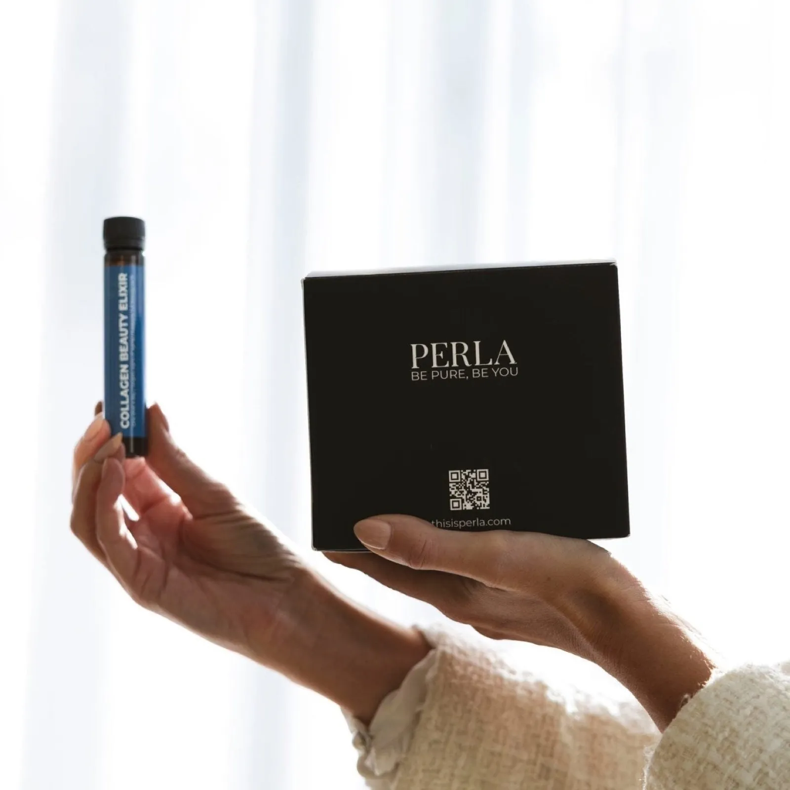 Main tenant une fiole de Collagen Beauty Elixir PERLA devant son coffret noir siglé