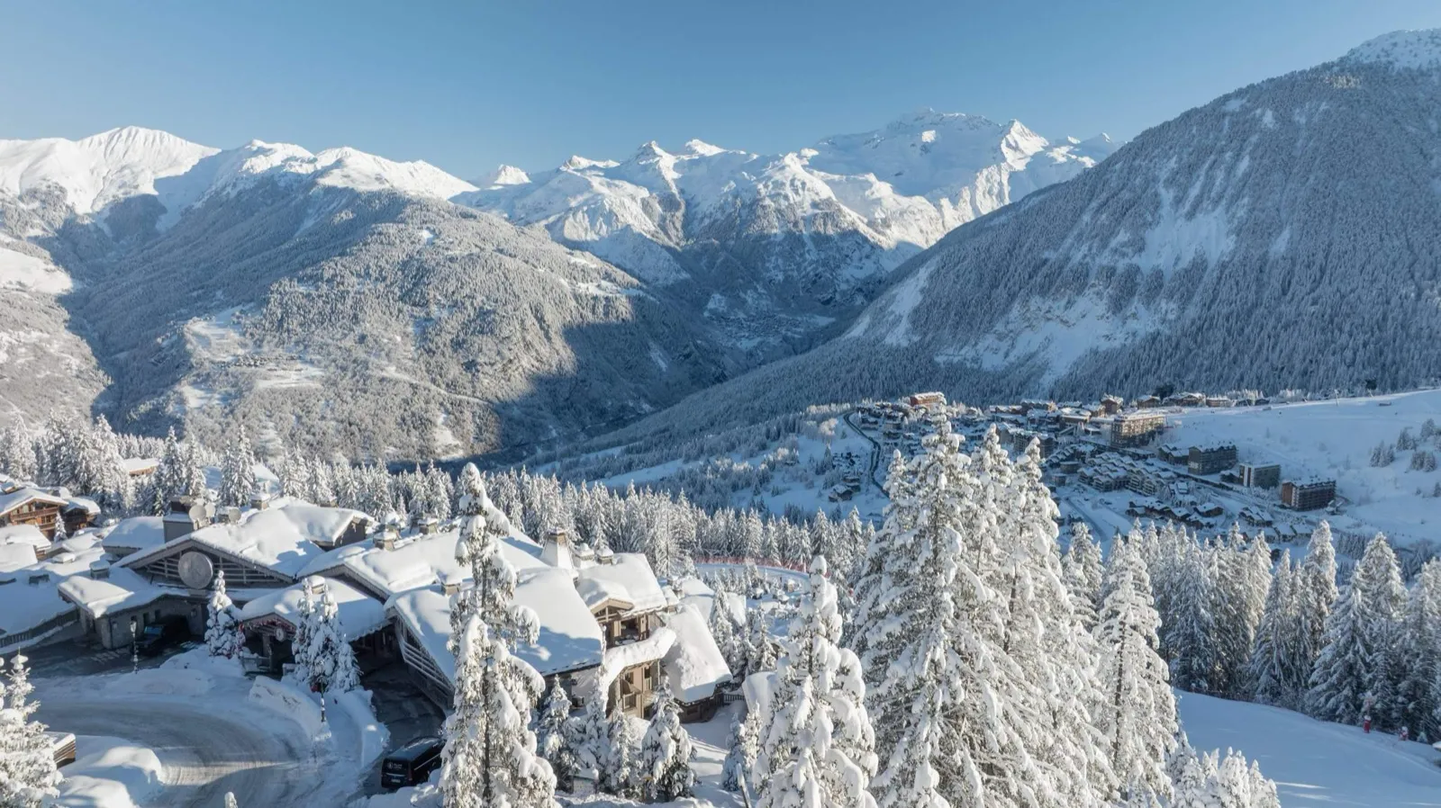 Vue aérienne du K2 Palace enneigé à Courchevel 1850 face aux sommets de la Vanoise