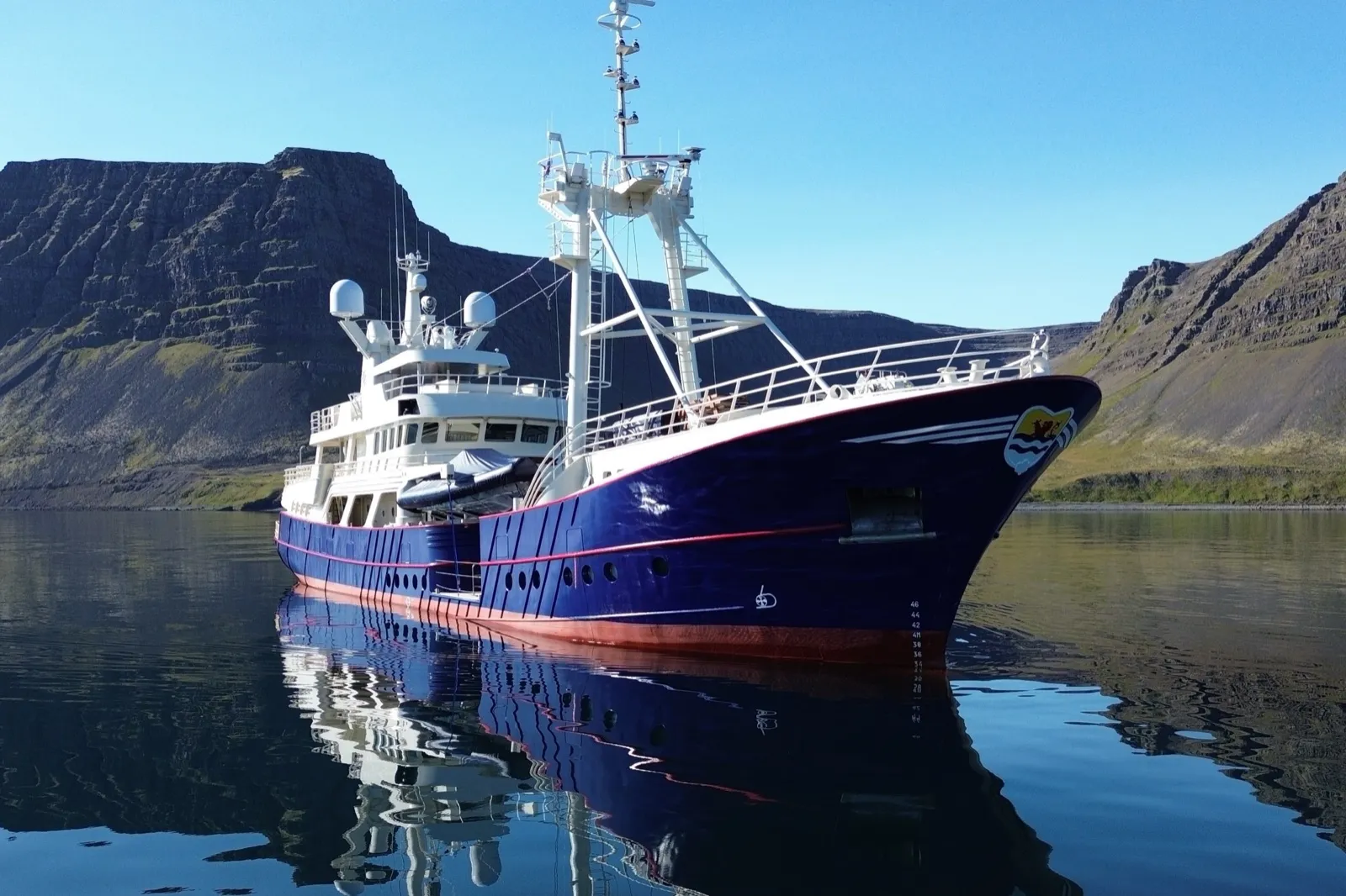 Super-yacht explorateur Damen Scintilla Maris de 45 mètres, coque bleu marine, au mouillage dans un fjord