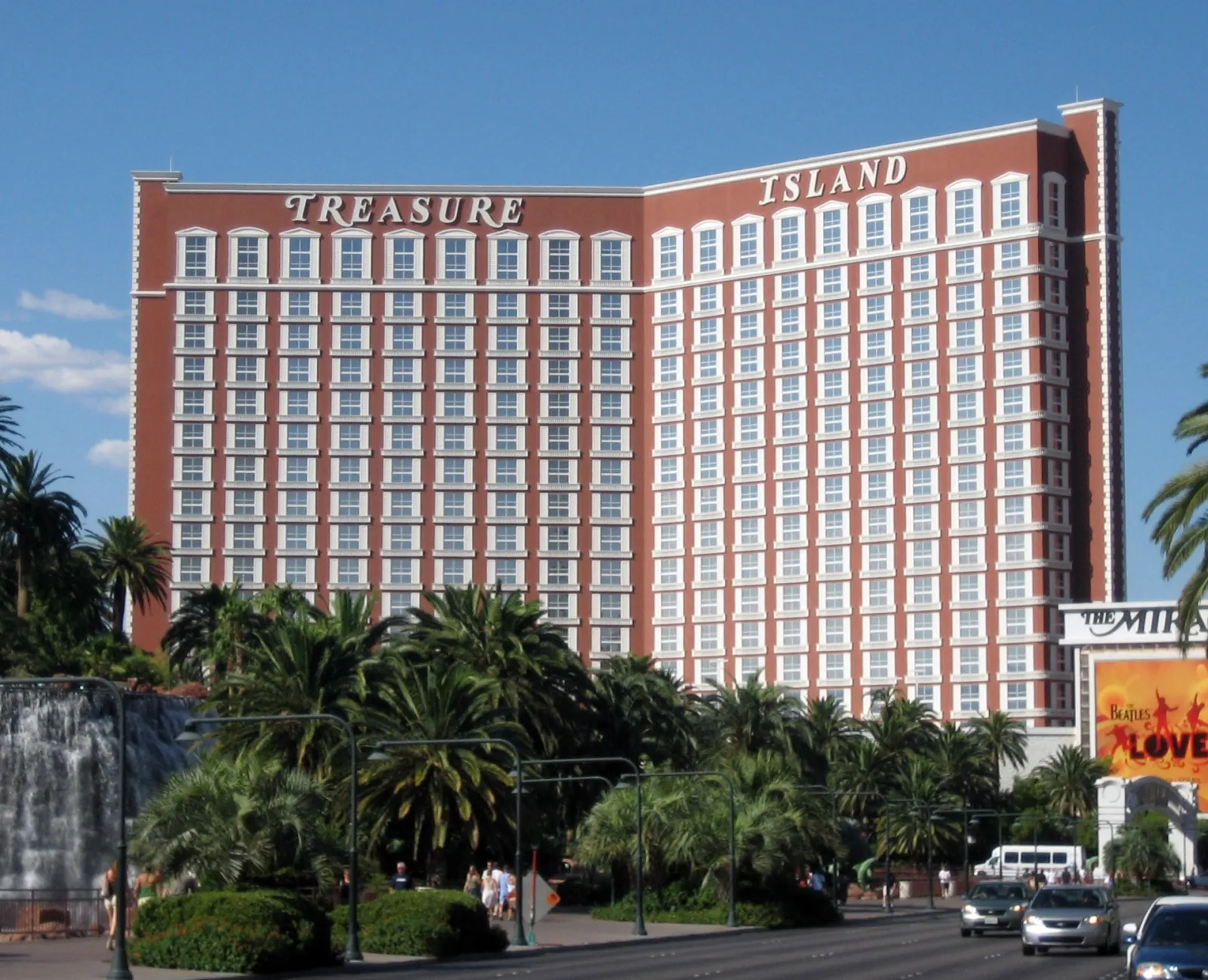 Tour rouge de l'hôtel Treasure Island à Las Vegas, entourée de palmiers, vue depuis le Strip