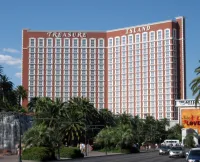 Tour rouge de l'hôtel Treasure Island à Las Vegas, entourée de palmiers, vue depuis le Strip