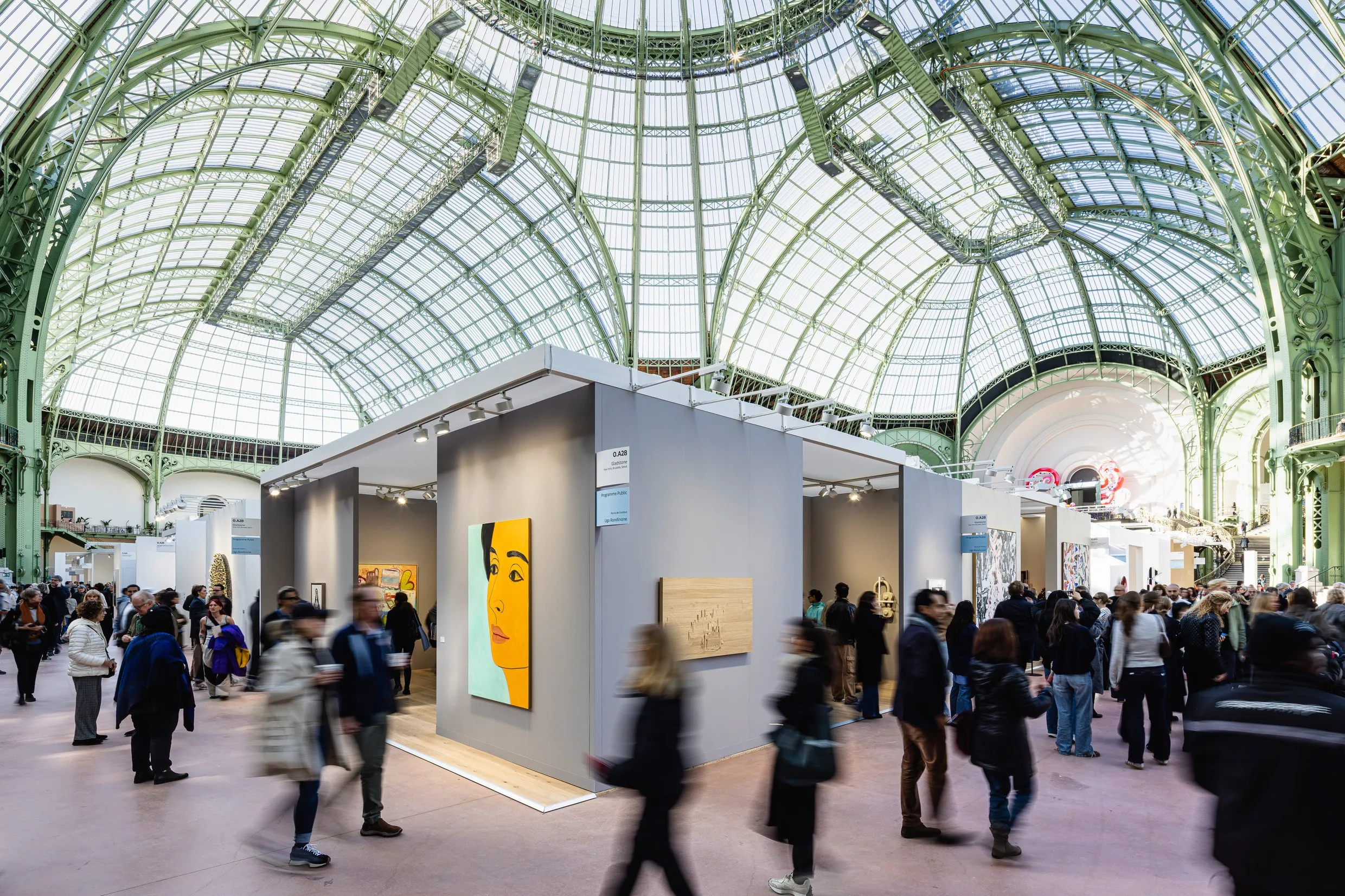 Visiteurs devant les stands d'Art Basel Paris 2025 sous la verrière du Grand Palais