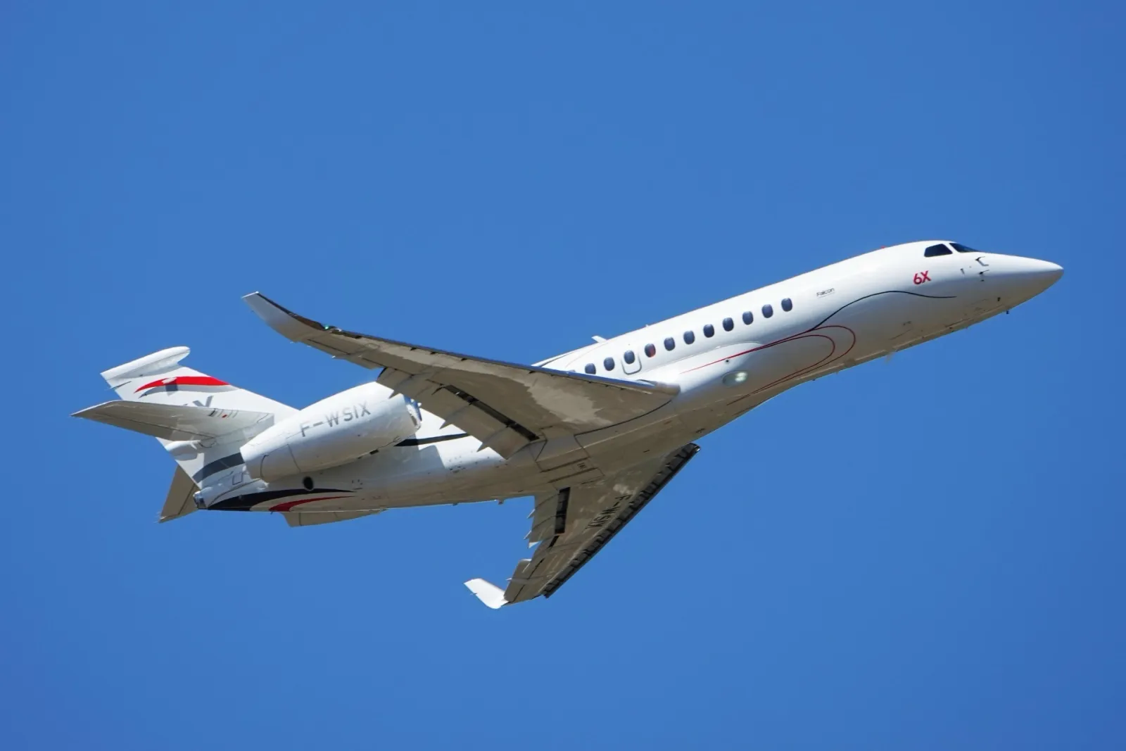 Jet d'affaires Dassault Falcon 6X en montée sous un ciel bleu lors du salon aéronautique du Bourget 2025