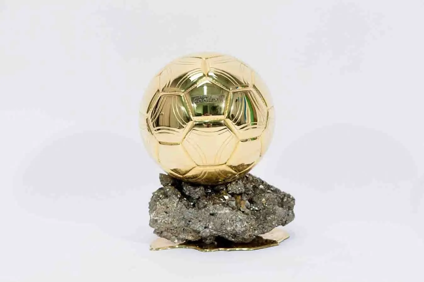Trophée du Ballon d'Or France Football : ballon en laiton doré posé sur un bloc de pyrite