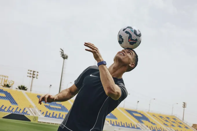 Cristiano Ronaldo jongle de la tête avec un ballon dans un stade, bracelet WHOOP au poignet