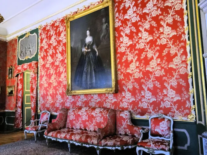Salon aux murs tendus de damas rouge à motifs floraux, portrait en pied et canapé assorti au palais de Nieborów