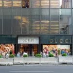 Boutique Gucci sur une grande avenue new-yorkaise, enseigne dorée et façade vitrée de l'immeuble