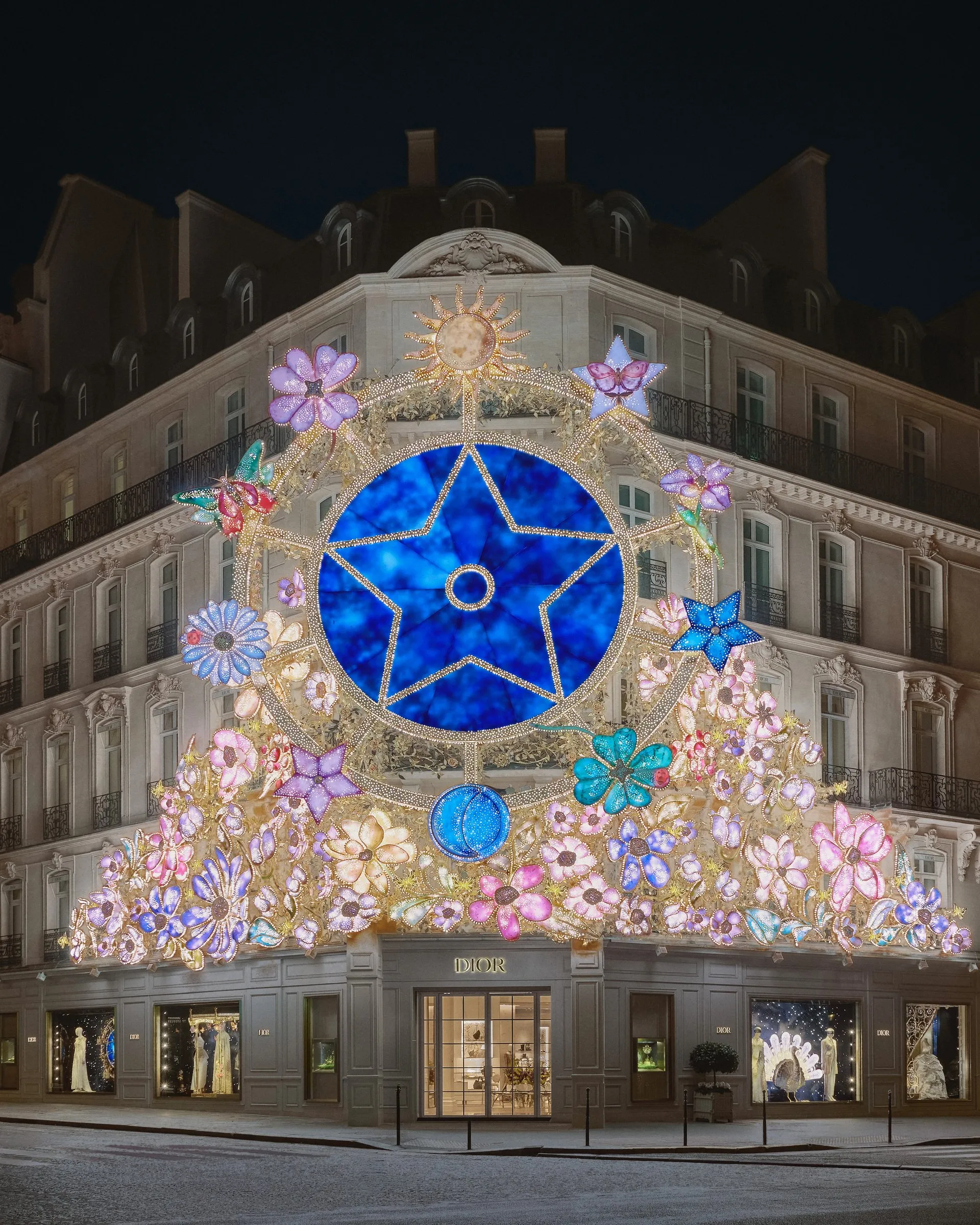 Façade illuminée de Dior au 30 avenue Montaigne pour Noël 2025, avec une grande étoile bleue et des fleurs lumineuses