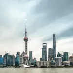 Skyline de Pudong à Shanghai, avec la tour de la Perle de l'Orient, vue depuis la rive du Huangpu sous un ciel nuageux