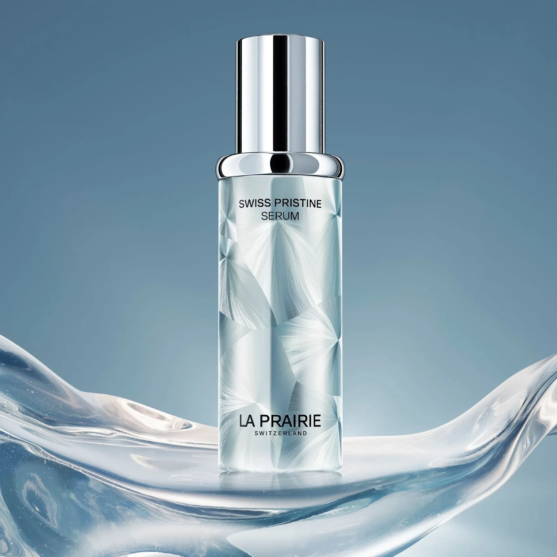 Frasco plateado del sérum Swiss Pristine de La Prairie sobre una ola translúcida