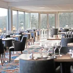 Salle du restaurant Le Panoramique du Domaine de la Corniche, tables dressées et baies vitrées sur la vallée de la Seine