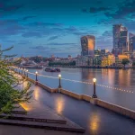 Les berges de la Tamise à Londres au crépuscule, l'hôtel de ville en forme de dôme et les tours de la City au loin