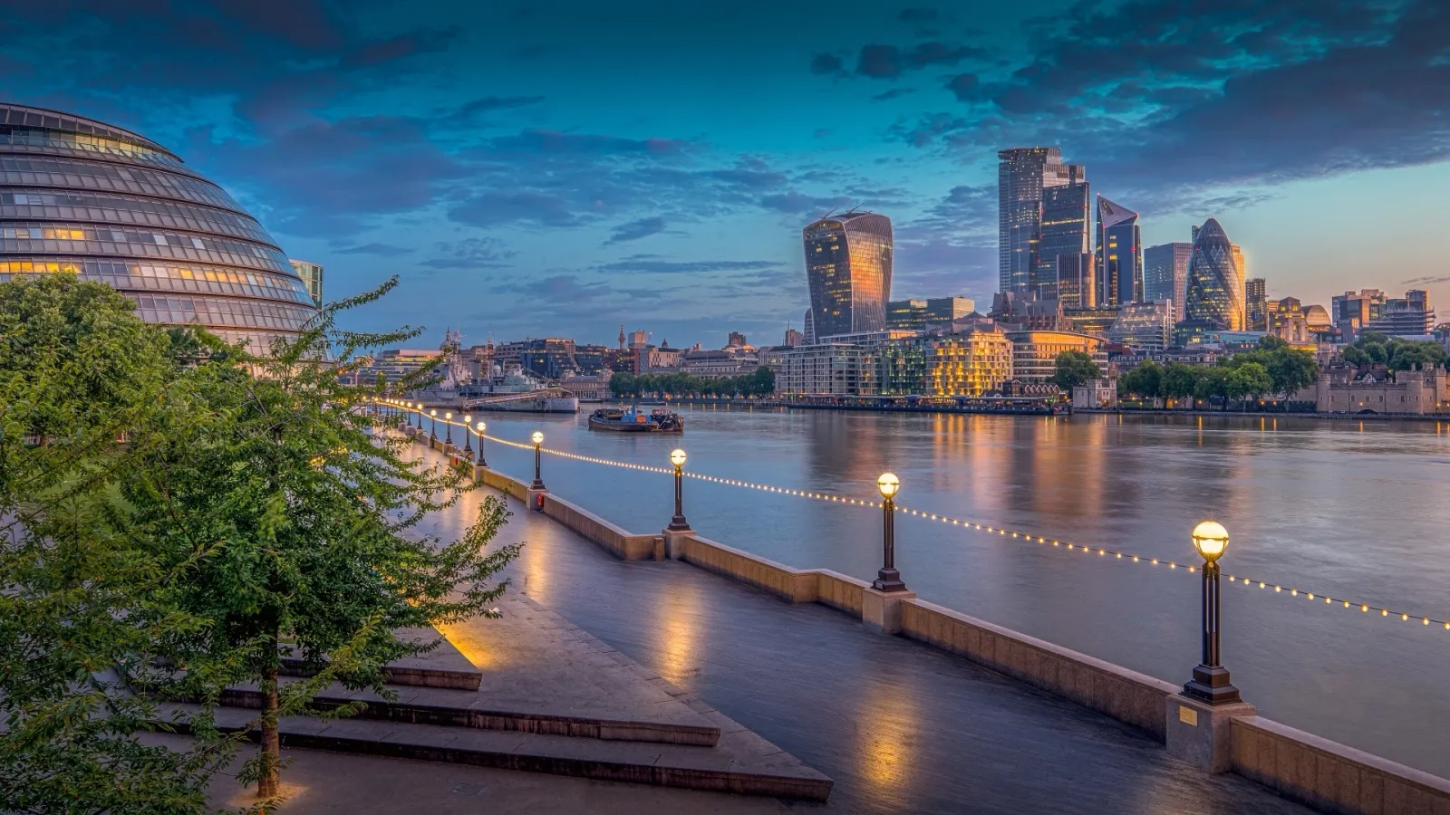 Les berges de la Tamise à Londres au crépuscule, l'hôtel de ville en forme de dôme et les tours de la City au loin