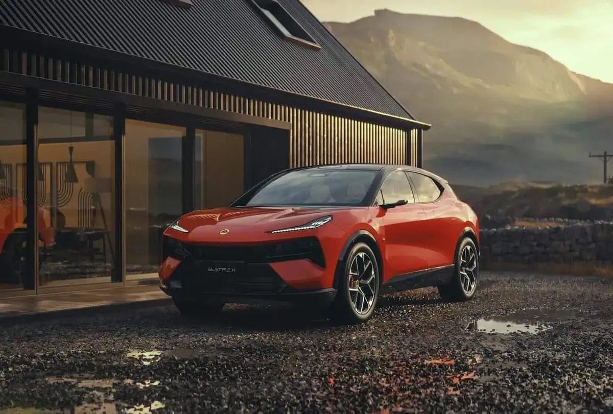 Lotus Eletre X rouge garé devant une maison en bois au pied d'une montagne