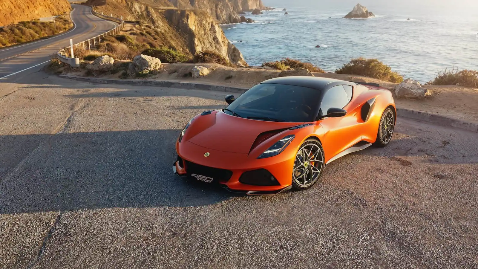 Lotus Emira 420 Sport orange sur une route côtière