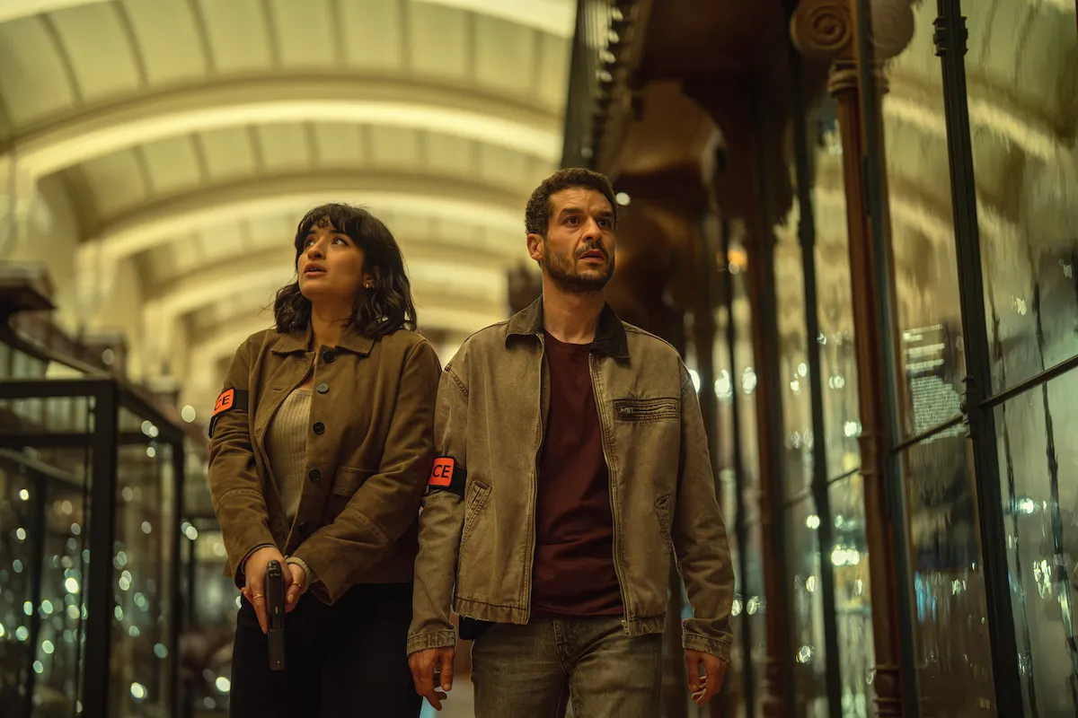 Shirine Boutella et Soufiane Guerrab, brassards de police, dans une galerie de musée aux vitrines éclairées, Lupin partie 4