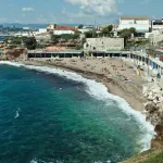 Vue sur la plage de Bonne Brise à Marseille, mer turquoise, rivage rocheux et immeubles en bord de mer