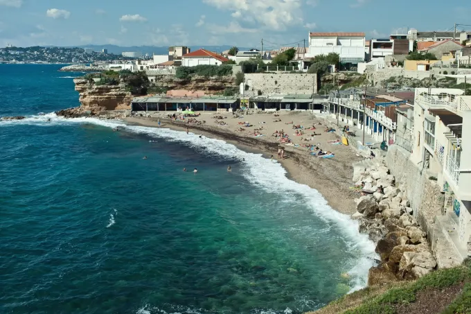 Vue sur la plage de Bonne Brise à Marseille, mer turquoise, rivage rocheux et immeubles en bord de mer