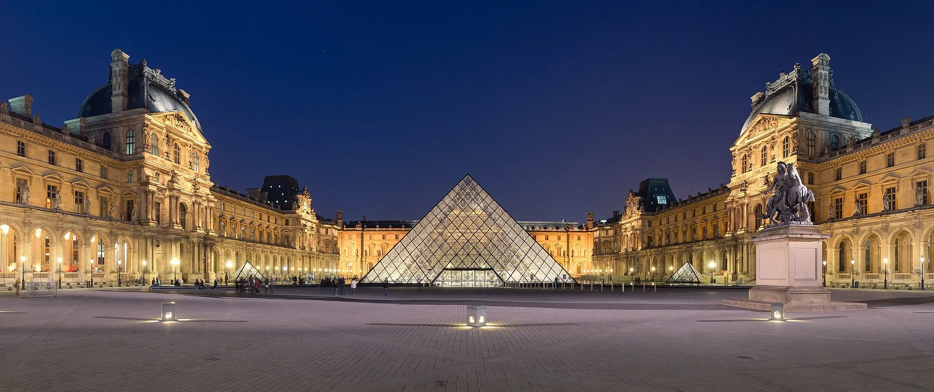 La pyramide du Louvre illuminée de nuit dans la cour Napoléon, décor du premier casse de la série Lupin