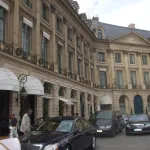 Façade classique du Ritz Paris place Vendôme, auvents blancs au rez-de-chaussée et berlines devant l'entrée
