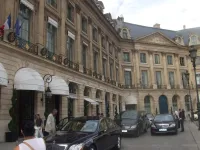 Façade classique du Ritz Paris place Vendôme, auvents blancs au rez-de-chaussée et berlines devant l'entrée