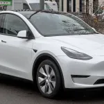 SUV électrique Tesla Model Y de couleur blanche garé dans une rue, vu de trois quarts avant