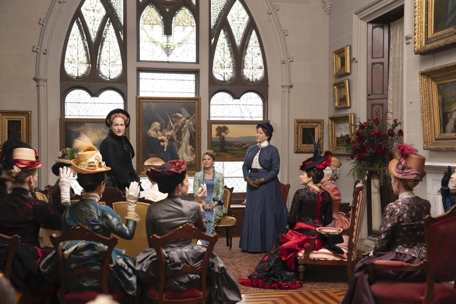 Femmes en tenues des années 1880 réunies dans la galerie de tableaux de Lyndhurst, sous de grands vitraux