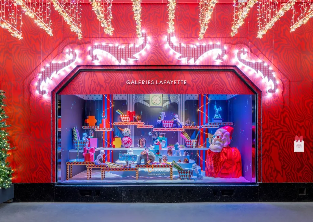 Vitrine de Noël rouge des Galeries Lafayette Haussmann en 2025, avec un Père Noël géant et des objets Christofle