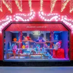 Vitrine de Noël rouge des Galeries Lafayette Haussmann en 2025, avec un Père Noël géant et des objets Christofle