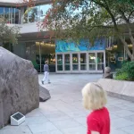 Cour intérieure et entrée vitrée du National Geographic Museum à Washington, avec un rocher et des visiteurs